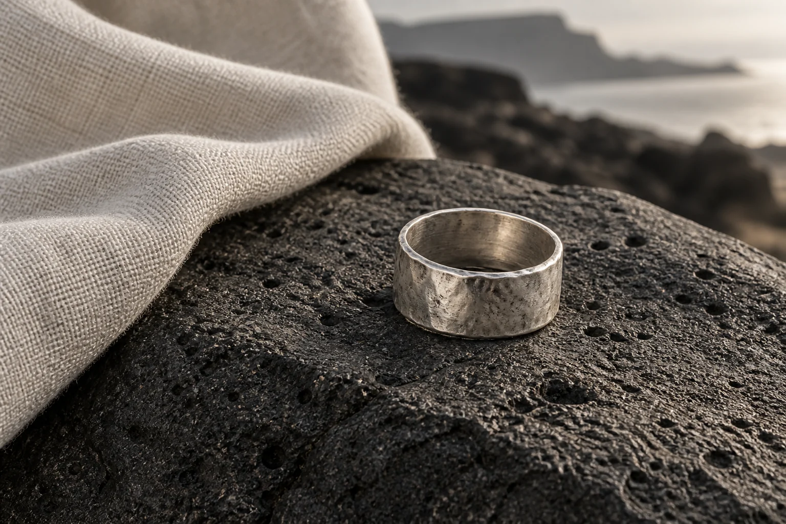Editorial illustration of a hand-worked silver ring on volcanic stone